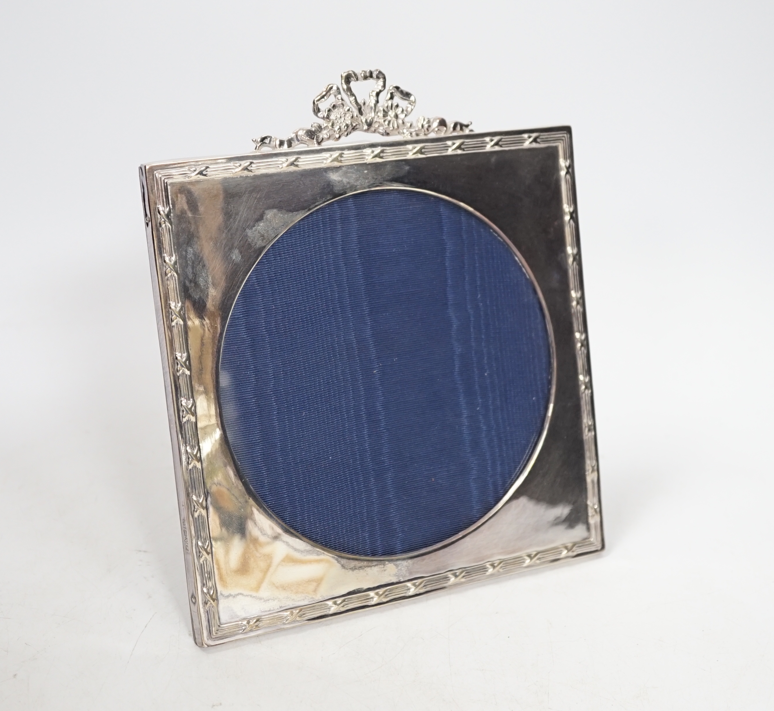 An Edward VII silver easel photograph frame with ribbon crest and circular aperture, Chester 1906, 20cm